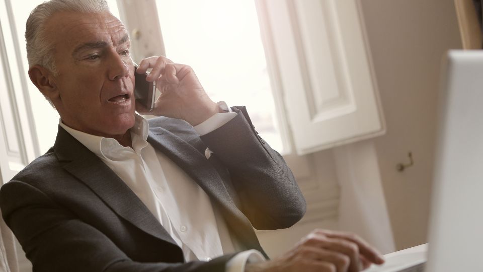 Hombre mayor de negocios hablando por teléfono mientras trabaja en jubilación activa